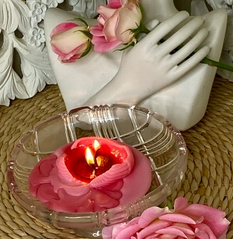 Pink pool of melted wax and the answer coin with twp flames glowing.  Two beautiful pink and white roses held by the hand of a statue on a natural circular wicker base table.
