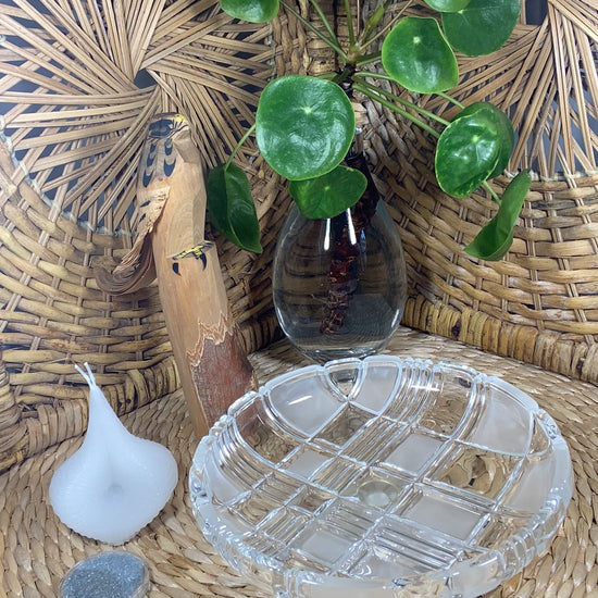 The video shows a white Destiny Decision Candle with a round coin sized container filled with Destiny Sparkles. There is a fireproof round glass plate placed on a natural wicker table and a wicker background.  A Japanese hand carved wood eagle and a clear vase with a healthy green money tree plant.

Demonstrating how to use the Destiny Decision Candle.  Pour the Destiny Sparkles onto the glass plate. Place the candle on top of the Destiny Sparkles.  Ask your yes or no question as you light the two wicks.
