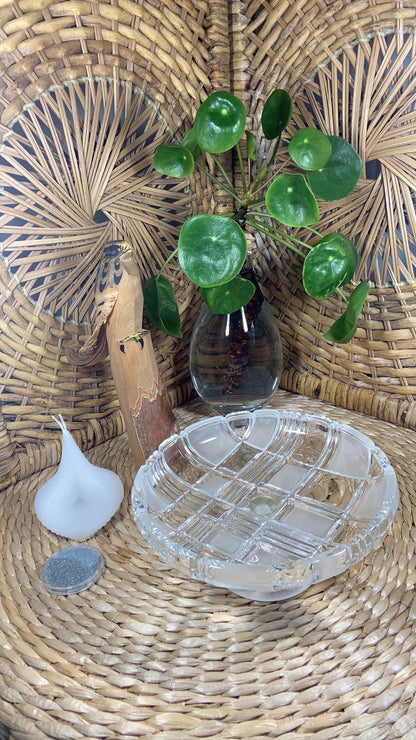 The video shows a white Destiny Decision Candle with a round coin sized container filled with Destiny Sparkles. There is a fireproof round glass plate placed on a natural wicker table and a wicker background.  A Japanese hand carved wood eagle and a clear vase with a healthy green money tree plant.

Demonstrating how to use the Destiny Decision Candle.  Pour the Destiny Sparkles onto the glass plate. Place the candle on top of the Destiny Sparkles.  Ask your yes or no question as you light the two wicks.
