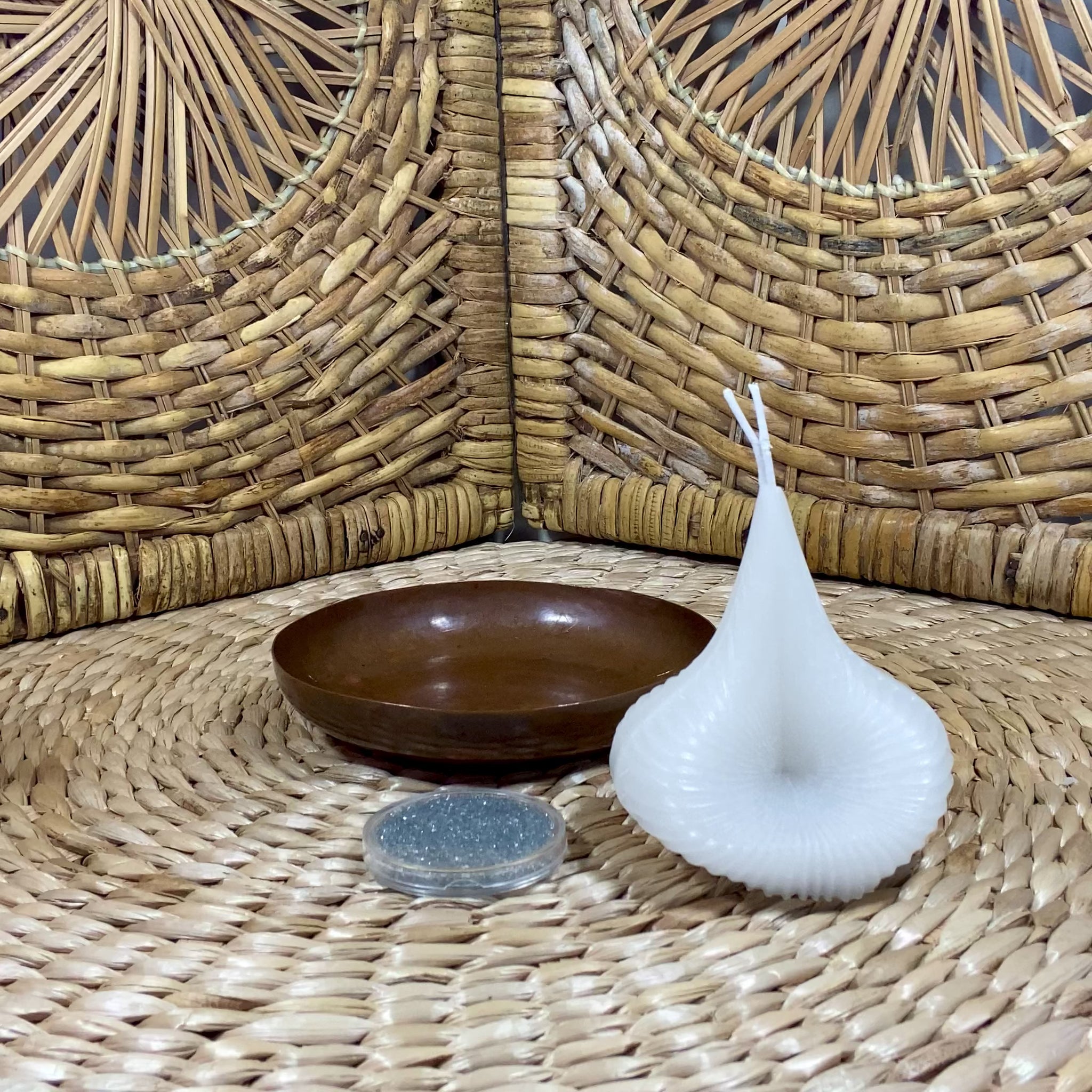 The video shows a white Destiny Decision Candle with a round coin sized container filled with Destiny Sparkles. There is a small fireproof copper bowl placed on a natural wicker table and a wicker background.

Demonstrating how to use the Destiny Decision Candle.  Pour the Destiny Sparkles into the copper bowl.  Place candle on top of the Destiny Sparkles.  Ask your yes or no question as you light the two wicks.
